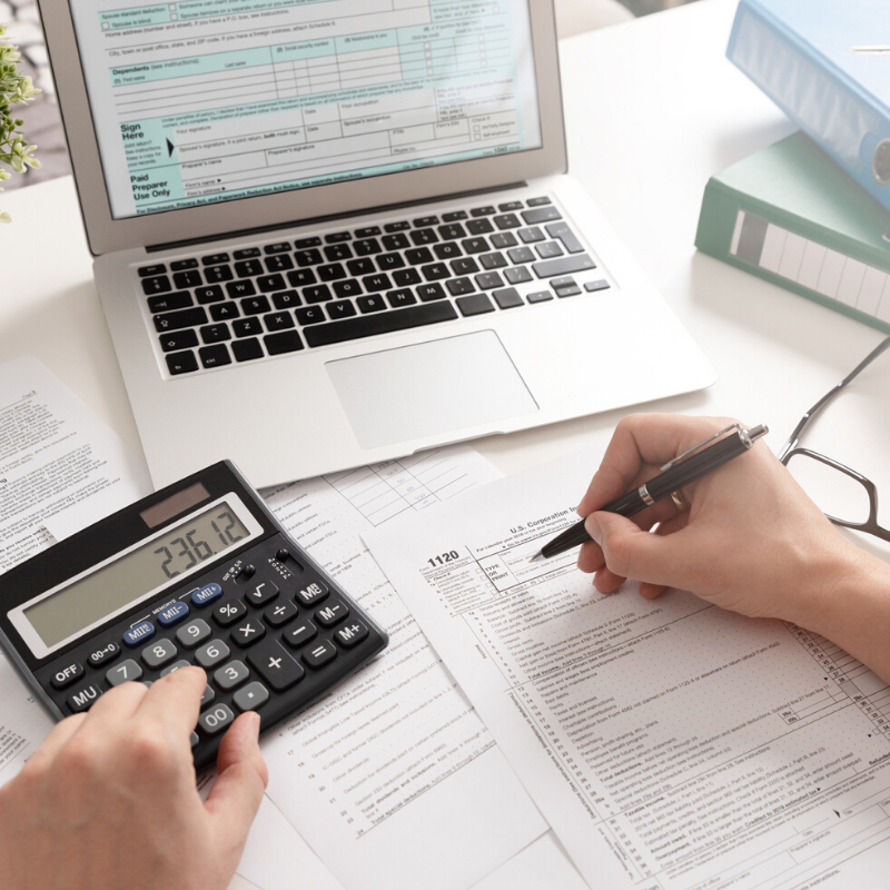 Desk top showing laptop, calculator and paperwork